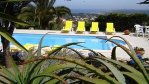 Ein Pool mit gelben Liegestühlen und Blick aufs Meer.