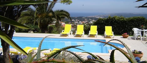 A pool with yellow lounge chairs and a view of the ocean.