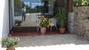 Eine Terrasse mit Glastür, Blumentöpfen und einer Steinsäule.