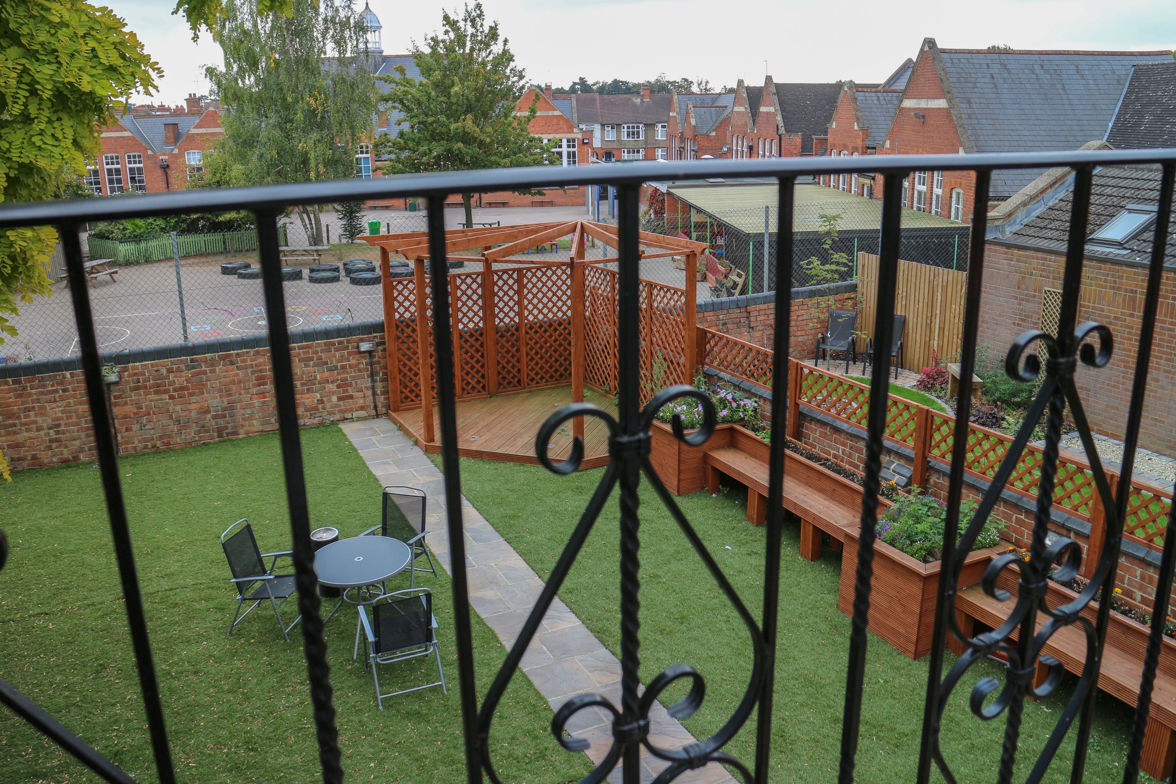 A fenced backyard with a patio area, outdoor seating, and a basketball court.