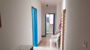 A hallway with a blue door, white chairs, and a patterned floor.