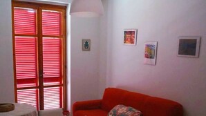 A room with a dining table, a red sofa, and a patterned floor.