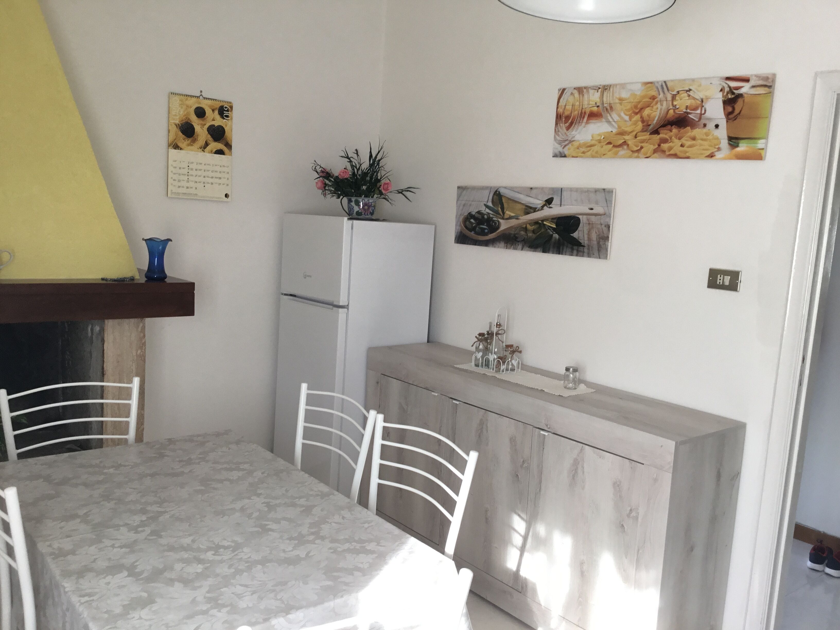 Ein Essbereich mit Tisch, Stühlen, einem Kühlschrank und Wanddekorationen.