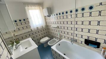 Une salle de bain avec une baignoire, deux lavabos, des toilettes et une douche.