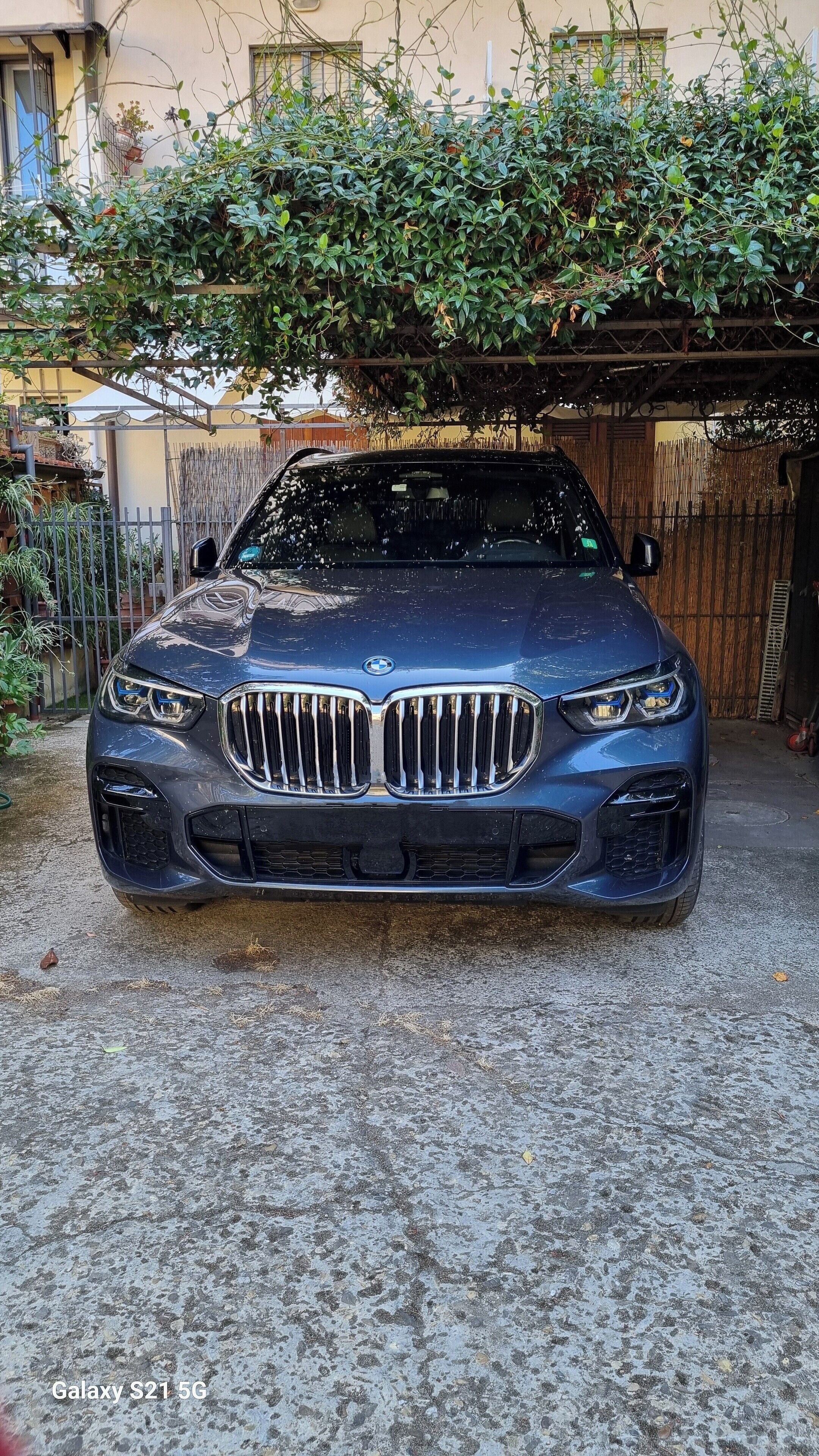 A blue BMW car parked in a driveway with a concrete surface.
