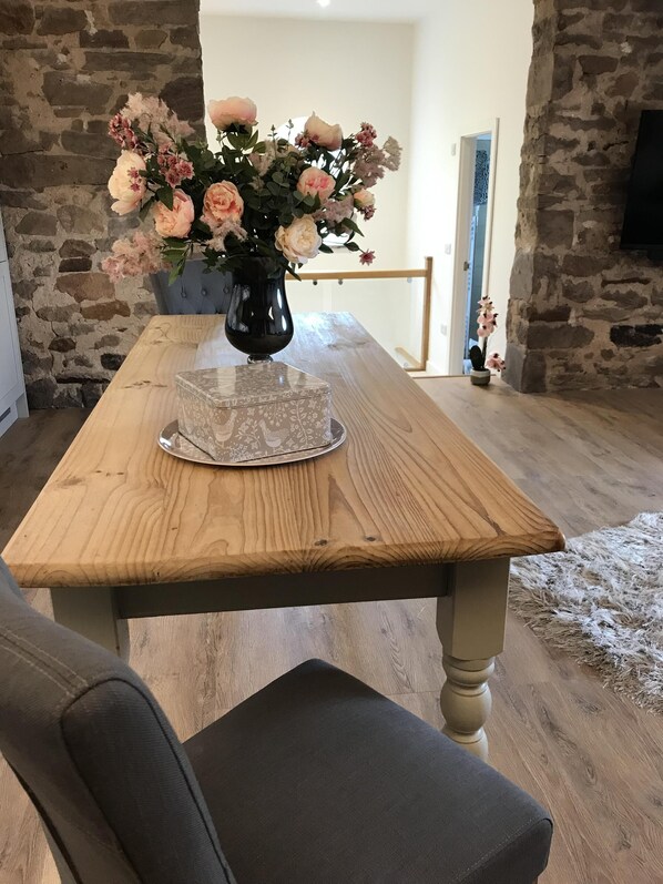 A wooden dining table with a vase of flowers and a decorative box.