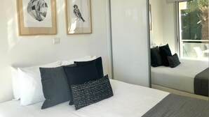 Ein modernes Hotelzimmer mit einem großen Bett, einem Balkon mit Blick und zwei gerahmten Bildern an der Wand.