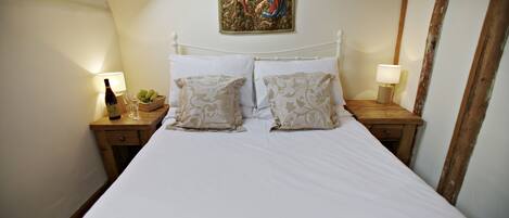 A neatly made bed with patterned pillows, a wall-mounted tapestry, and bedside lamps on wooden nightstands.