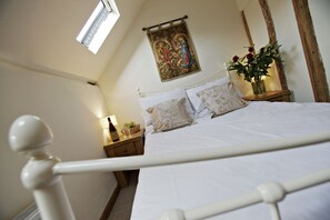 Un dormitorio con cama, mesita de noche, lámpara, ventana y un tapiz en la pared.