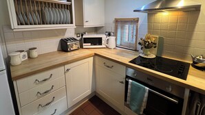 A compact kitchen with white cabinets, a microwave, a toaster, and a stove.
