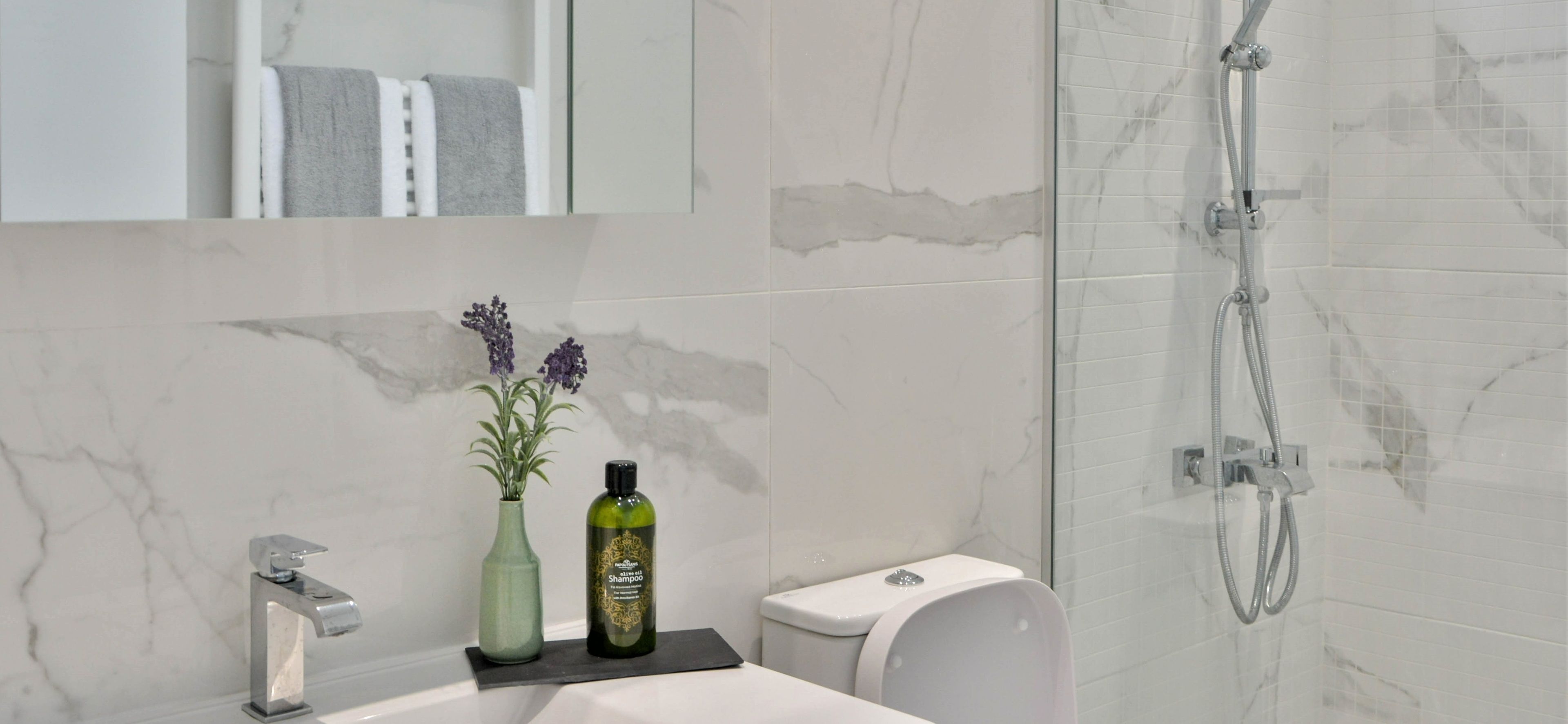 A modern bathroom with a marble sink, a shower, and a toilet.
