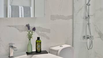 A modern bathroom with a marble sink, a shower, and a toilet.