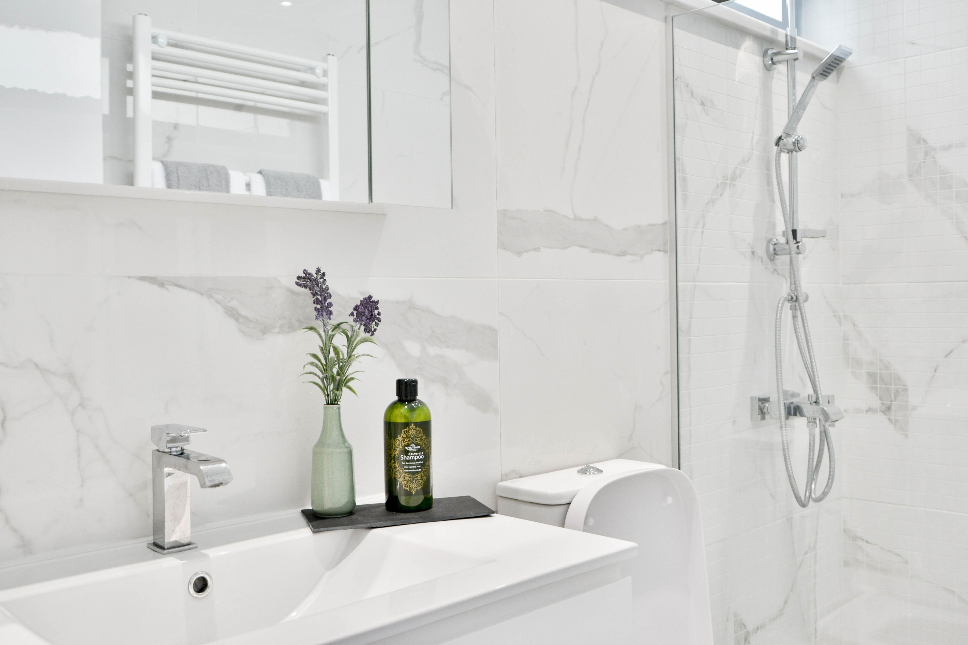A modern bathroom with a white sink, a glass shower enclosure, and a toilet.