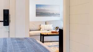 A room with a bed, a sofa, a coffee table, and a wall-mounted picture of a beach scene. - Morgan Hotel (Oak Bluffs)