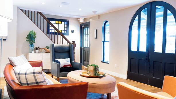 A spacious living room with a sofa, chairs, a coffee table, and a staircase. - Morgan Hotel (Oak Bluffs)