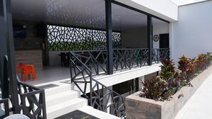 Een modern gebouw met een overdekt terras, een trap en een welkomstmat.