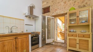 A kitchen with wooden cabinets, a stainless steel stove, and a glass-fronted cabinet with dishes. - SON BANUS - Chalet with private garden in Manacor. Free WiFi (Manacor)