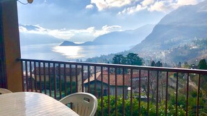 Een balkon met uitzicht op een meer, bergen en een stad.