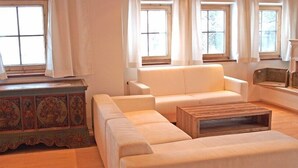 A living room with a sofa, a wooden coffee table, and a decorative cabinet. - Luxury Apartment Schoenbichl (Sankt Johann in Tirol)