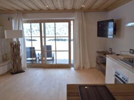 Una cocina moderna con un ventanal grande, un televisor de pantalla plana y un comedor con mesa y sillas.