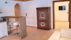 A modern kitchen with a wooden island, bar stools, and a decorative cabinet. - Luxury Apartment Schoenbichl (Sankt Johann in Tirol)