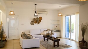 A spacious living room with a white sofa, a coffee table, and two hanging pendant lights.