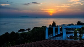 A coastal sunset view with a bridge and rocky outcrops. - Villa Rufola (Sorrento)