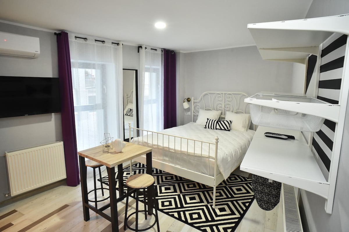 Une chambre à coucher avec un lit, un bureau, une chaise, un téléviseur et un radiateur.