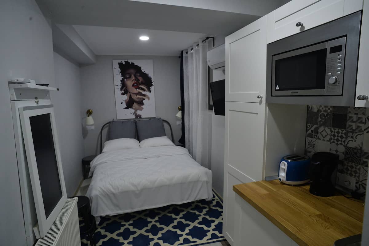 Une chambre d’hôtel compacte comprenant un lit, un four à micro-ondes, une machine à café et une petite kitchenette.