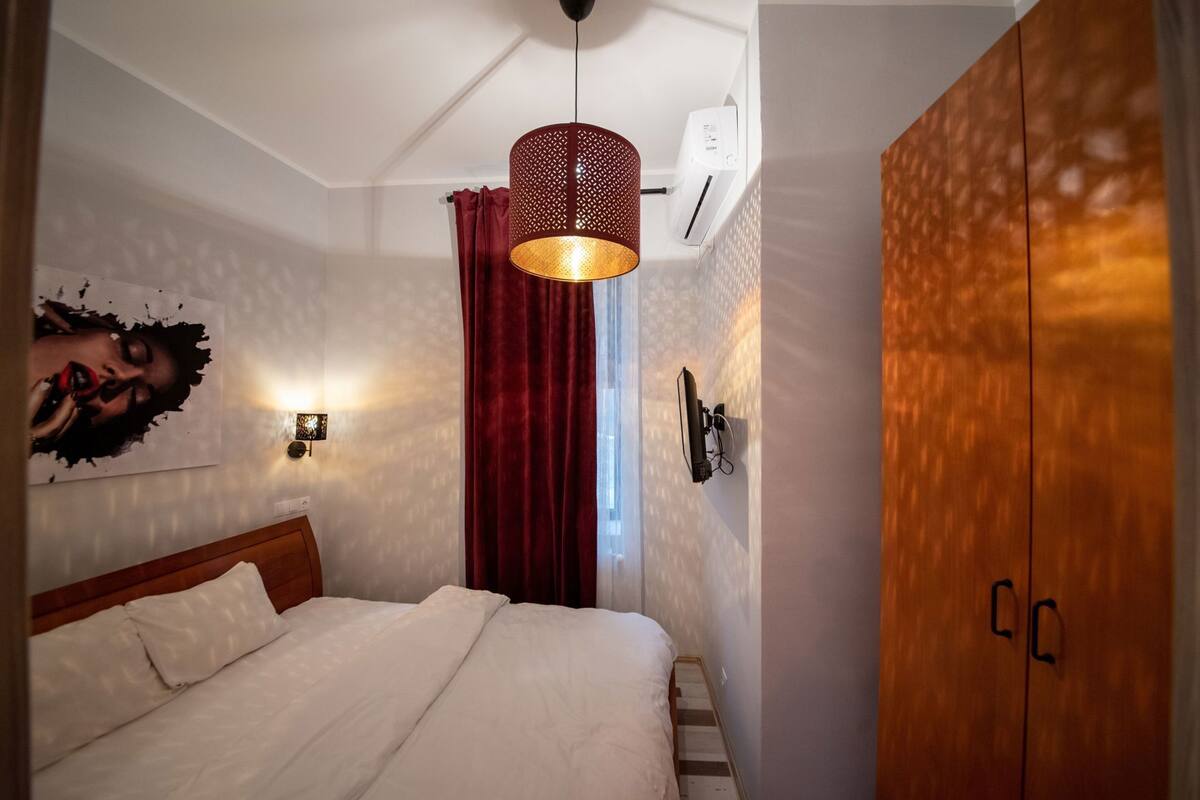 Une chambre à coucher comprenant un lit, un climatiseur fixé au mur, un luminaire au plafond et une armoire en bois.