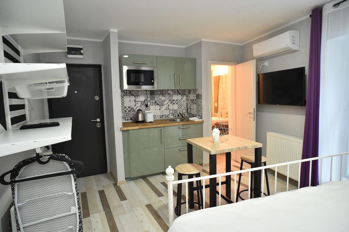Une chambre d’hôtel compacte comprenant un coin cuisine, un petit espace repas, un lit et une vue sur l’extérieur.