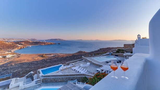 Ett semesterhotell med pool, solstolar och utsikt över havet.