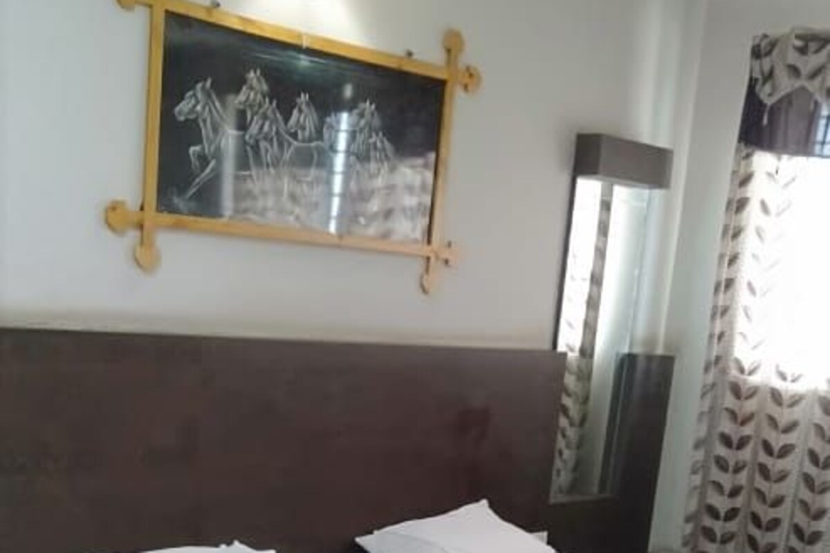 Ein Hotelzimmer mit einem großen Bett, einer Wandlampe und einem gerahmten Bild.