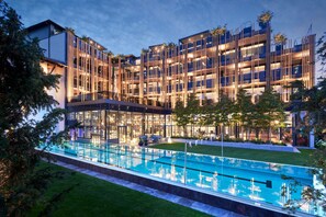 A modern hotel with a glass pool and outdoor seating area. - Wellness- & Sporthotel Jagdhof (Roehrnbach)