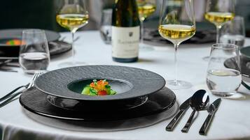 Una elegante disposición para comedor con un plato negro, mantel blanco y cristalería transparente.