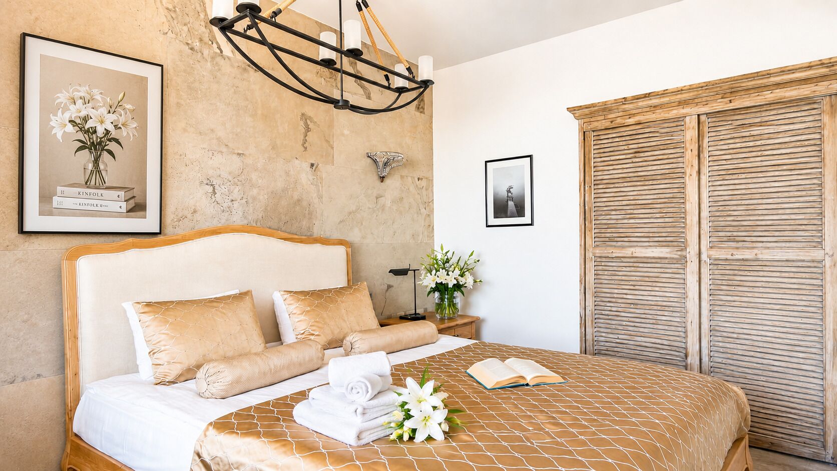 A hotel room with a bed, a nightstand, a wall-mounted light fixture, a framed picture, and a wooden door.