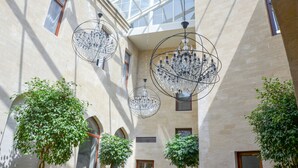 A spacious atrium with high ceilings, large windows, and hanging crystal chandeliers. - Shirvanshah Hotel (Baku)