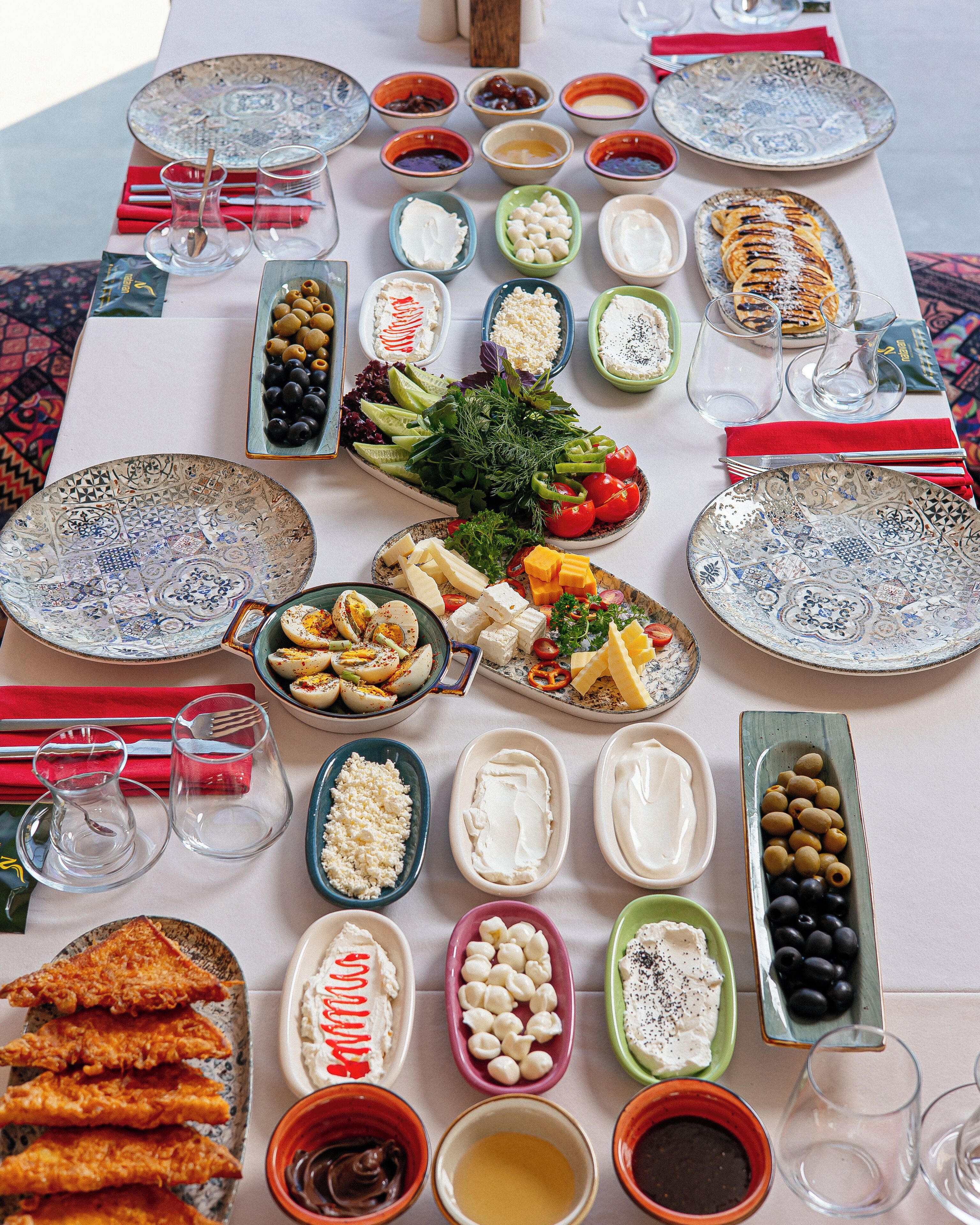 A table set with various dishes, including olives, cheese, and bread, suggesting a meal setting.