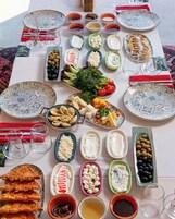Una mesa servida con varios platos, incluyendo aceitunas, queso y pan, que sugiere un ambiente para comer.