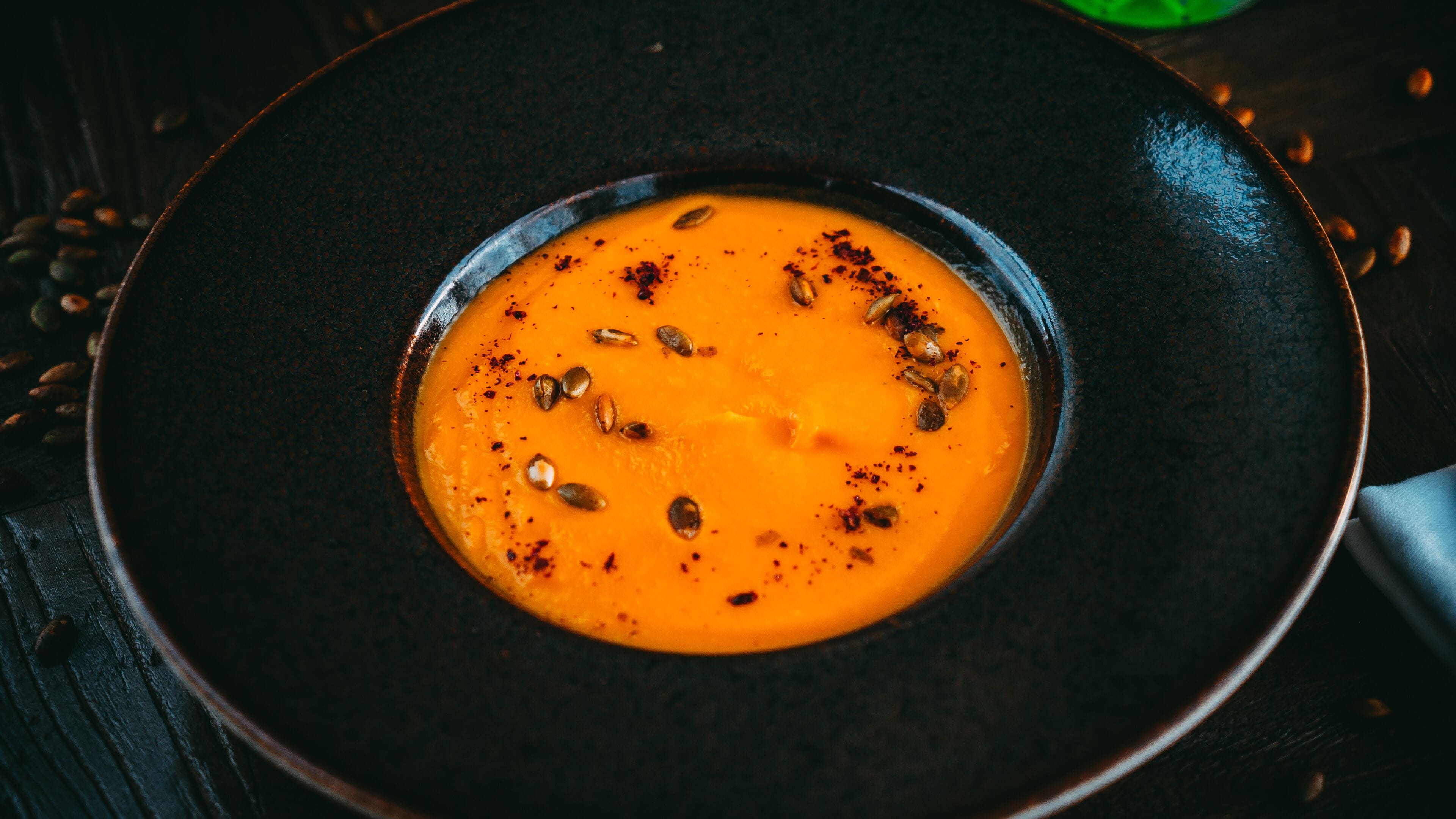 A bowl of soup garnished with seeds and spices.