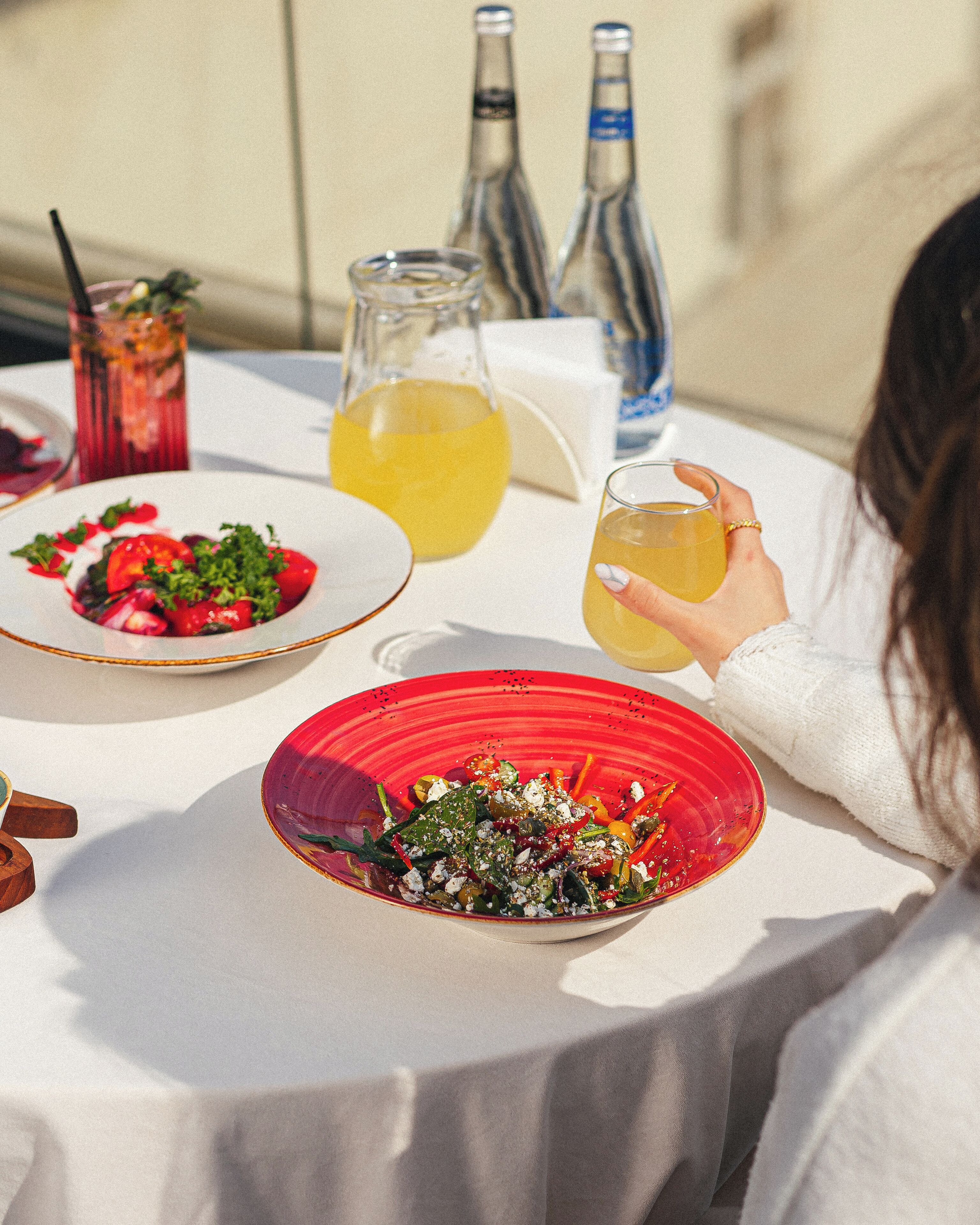 A table with two plates of food, a glass of drink, and two bottles of water.