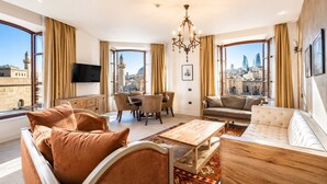 A spacious living room with a city view, a chandelier, and a dining area. - Shirvanshah Hotel (Baku)