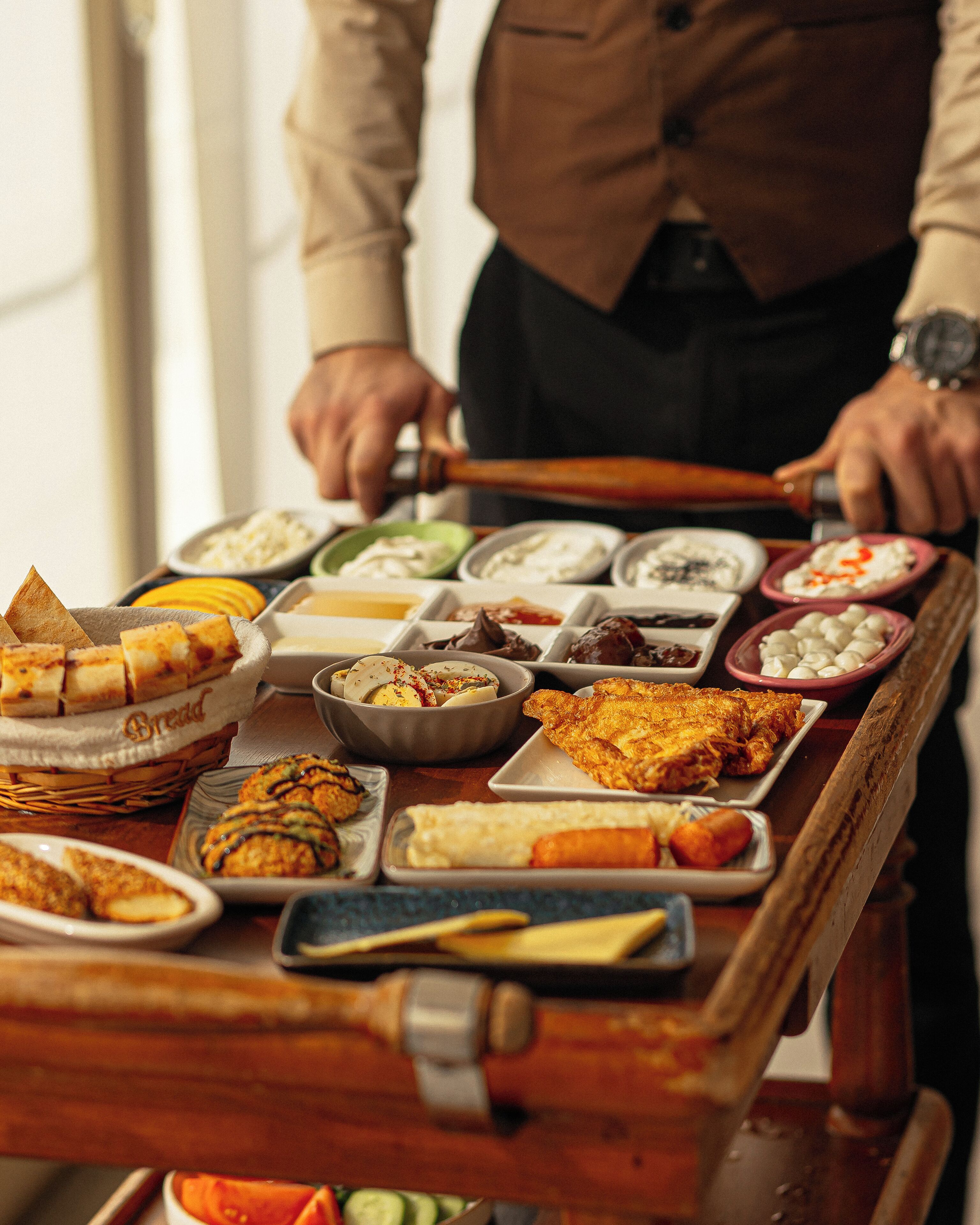 Une table de buffet garnie de différents plats, et une personne qui sert les aliments.
