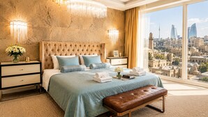A bedroom with a large bed, bedside tables, a bench, and a city view. - Shirvanshah Hotel (Baku)