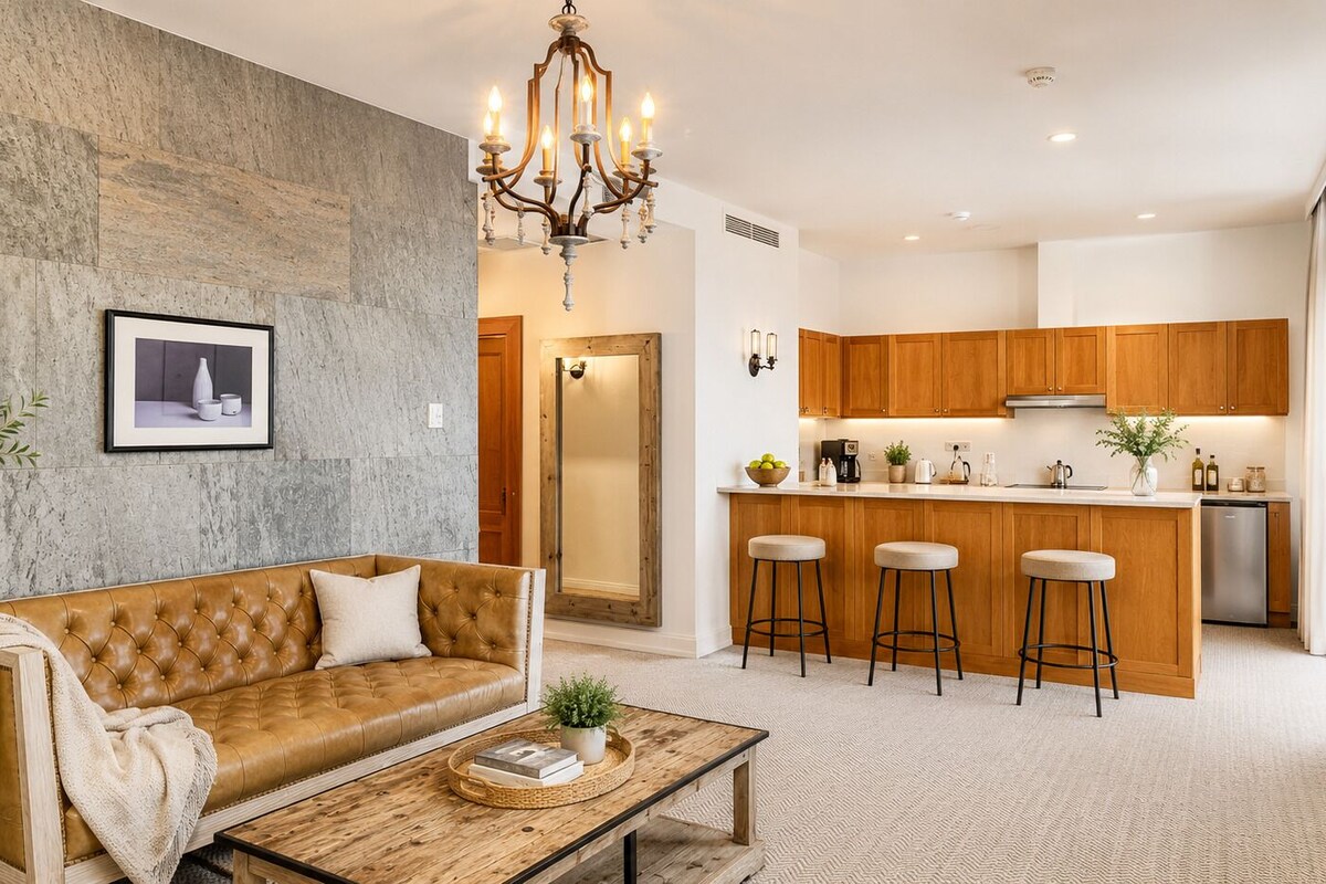 A modern living room with a leather sofa, a wooden coffee table, and a chandelier.