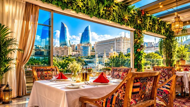 A dining area with a table set for two, a cityscape view through large windows, and a ceiling adorned with greenery. - Shirvanshah Hotel (Baku)