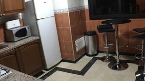 Una cocina equipada con refrigerador, microondas y taburetes de bar.