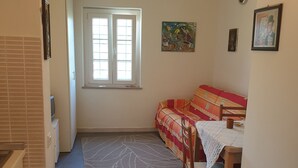 Een slaapkamer met een bed, een raam en een kunstwerk aan de muur.
