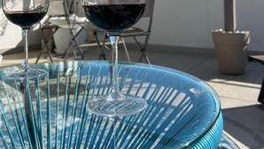 To vinglas på et blåt fletbord under et pergola med hængende planter.