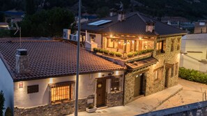 Uma casa de dois andares com telhado ladrilhado, varanda e fachada de pedra.